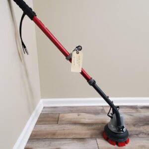 A red and black MotorScrubber Jet3 sitting on a wooden floor.