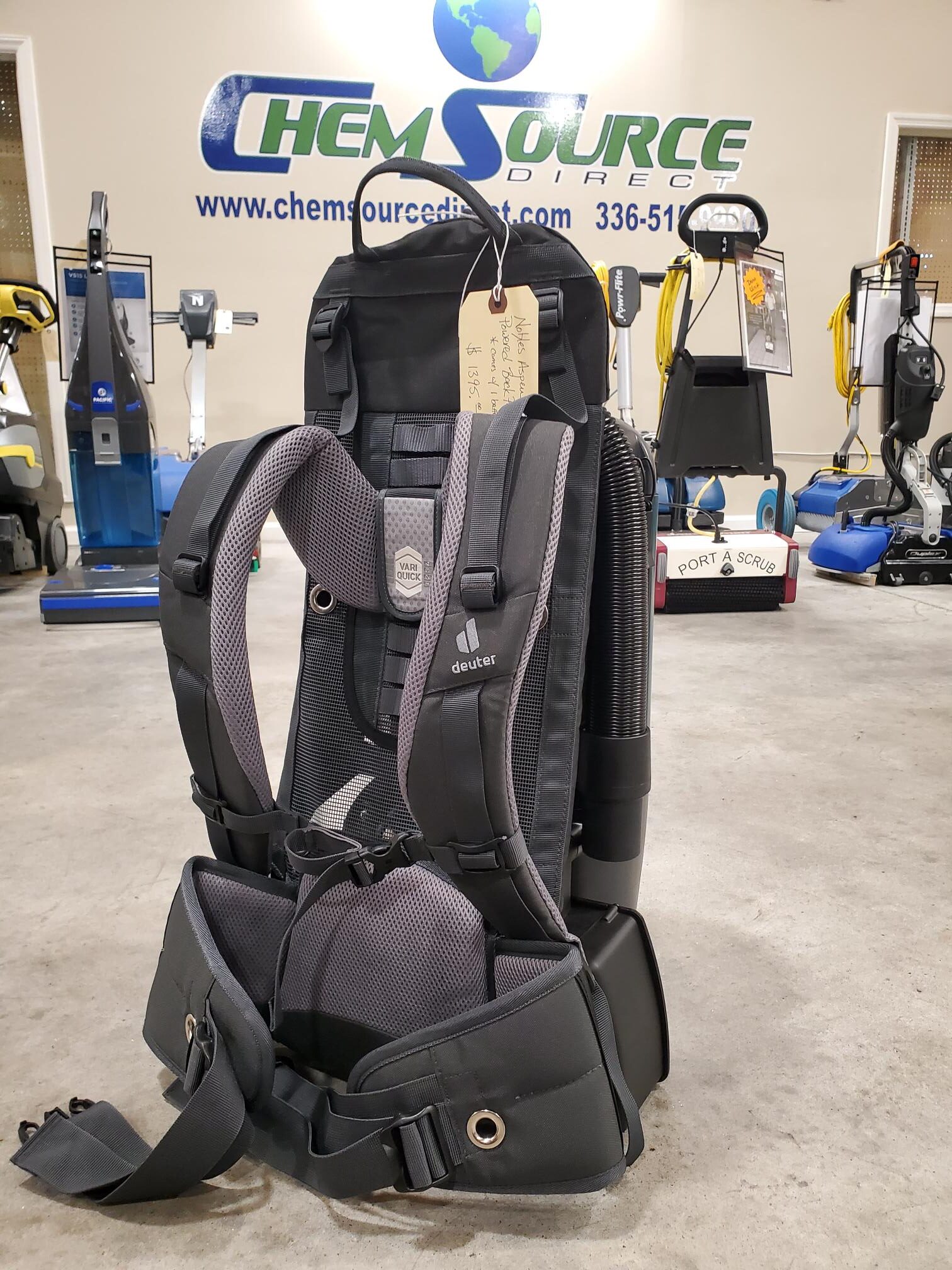 A Nobles Aspen 6B 6qt Battery Powered Backpack Vacuum NEW is sitting on a floor in a store.