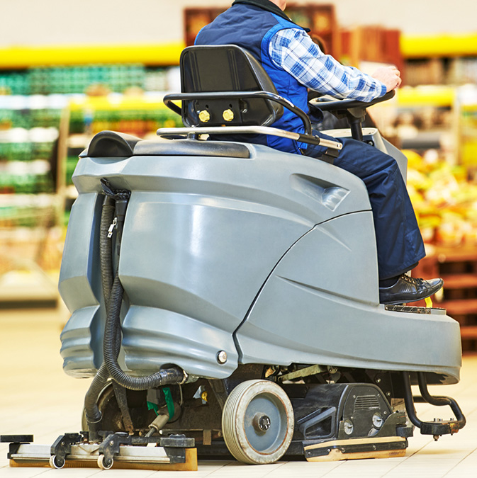 A man on a Ride-On Scrubber/Sweeper in a grocery store