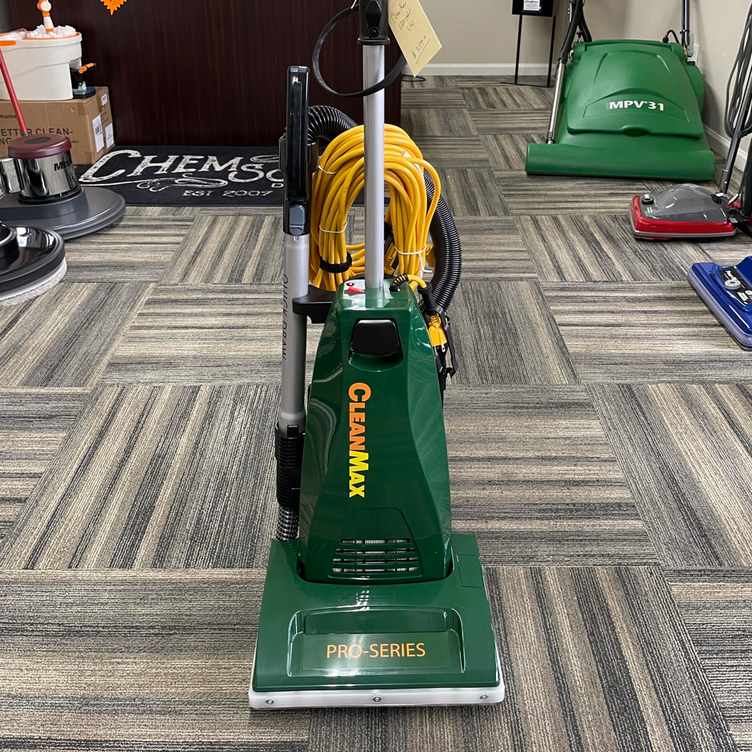 A green vacuum cleaner sitting on a carpet in a store.