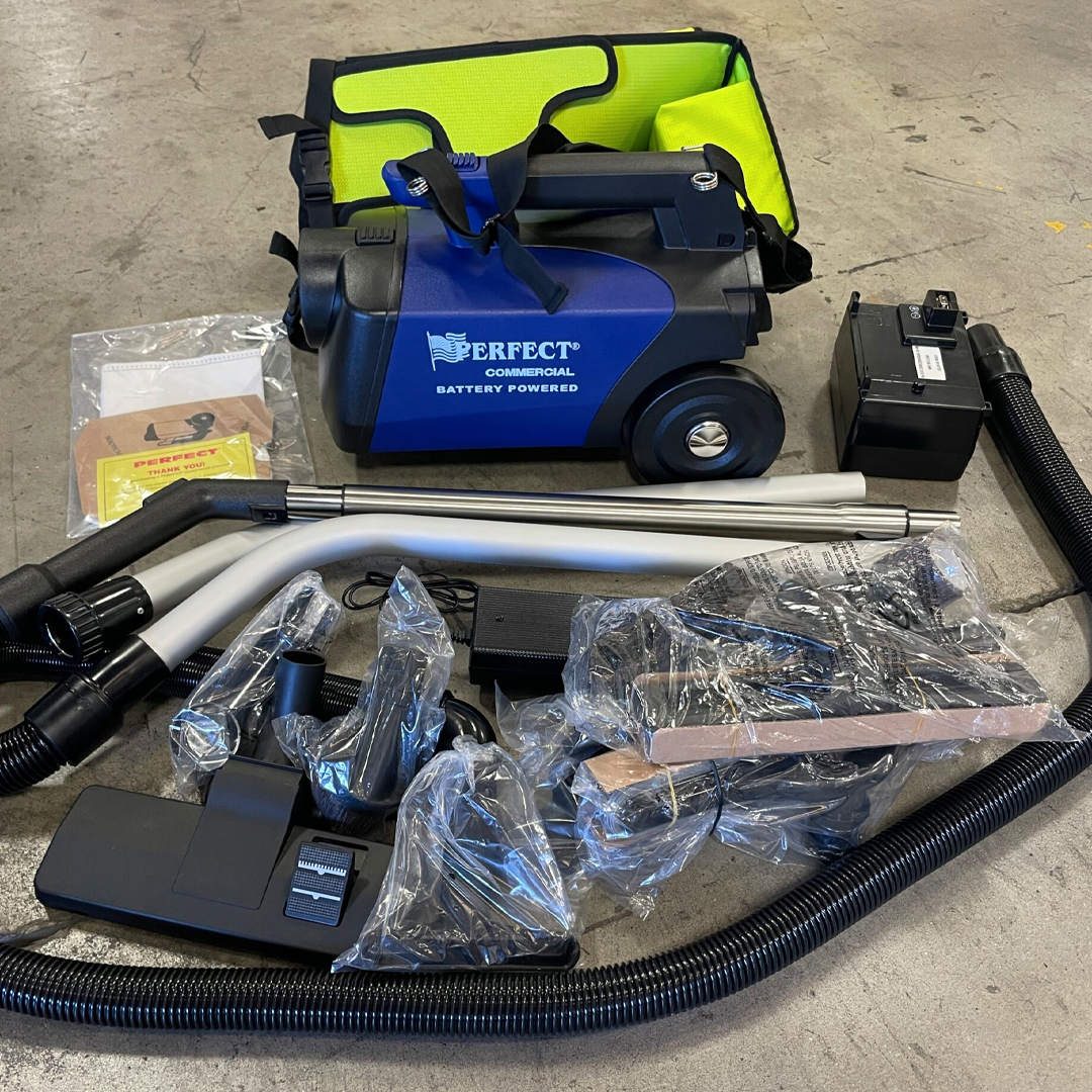 A vacuum cleaner with hoses and accessories on a concrete floor.