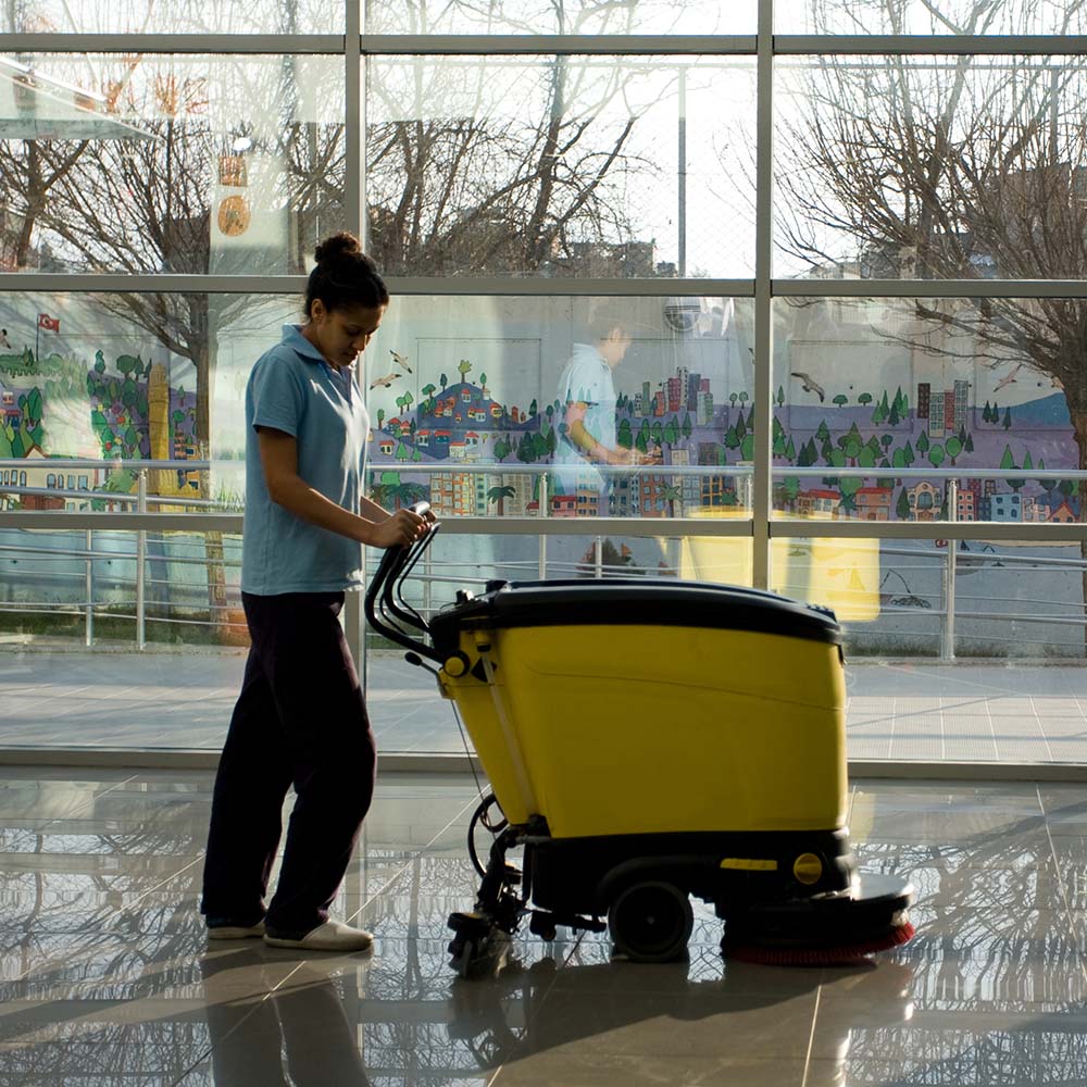 A woman cleaning a floor with a machine.