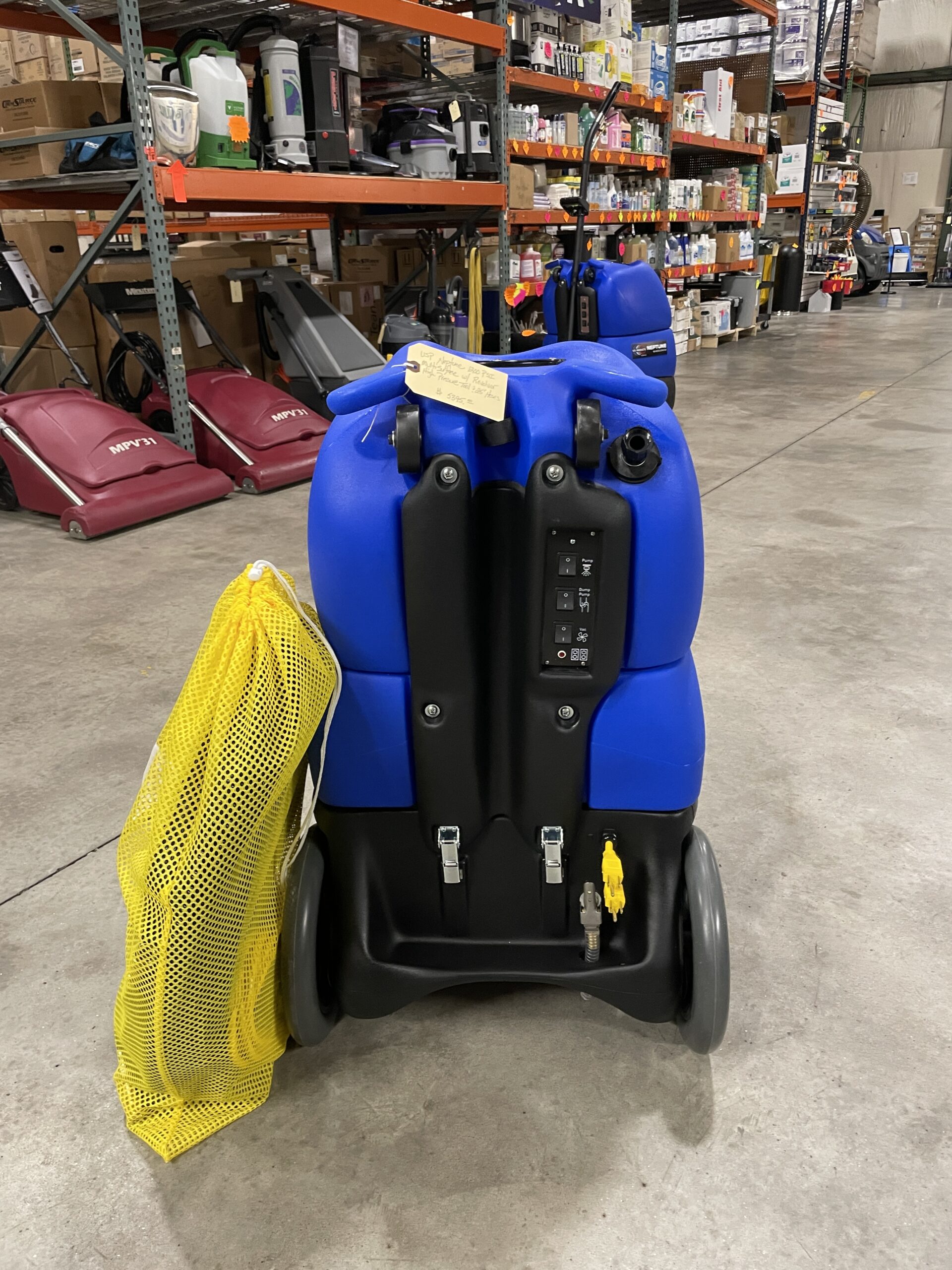 A US Products Neptune 1200PSI Multi Surface Cleaner w/ Revolver High Pressure Tool $ 25' Hoses NEW cart with a yellow bag sitting in a warehouse.