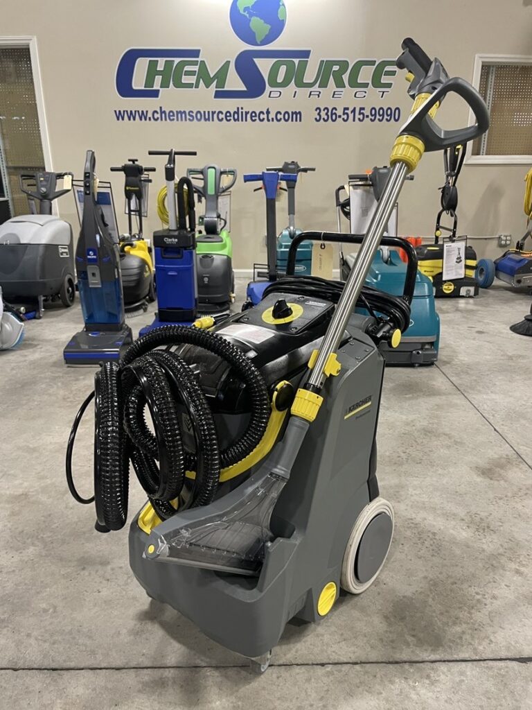 Karcher Puzzi Spray Extractor with accessories in a warehouse in front of scrubbers.