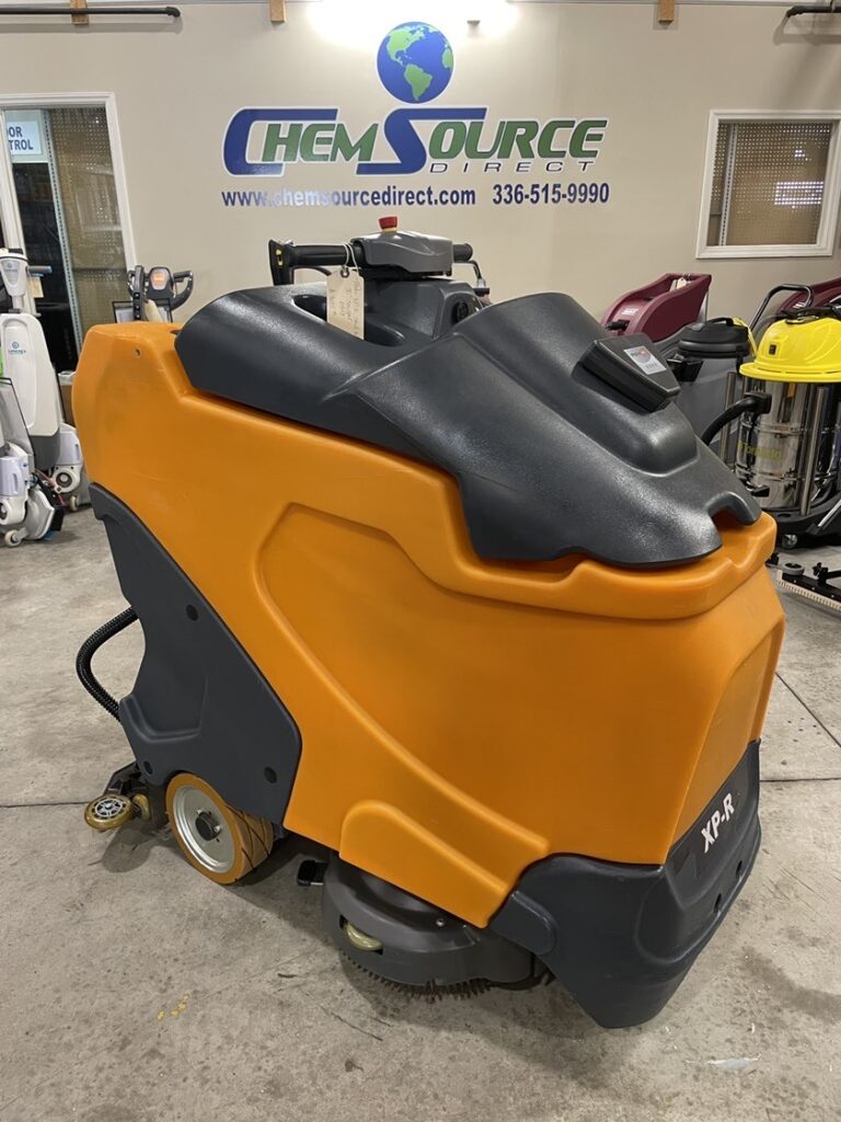 A Taski XP-R 30" Stand-On Scrubber in a warehouse showroom.