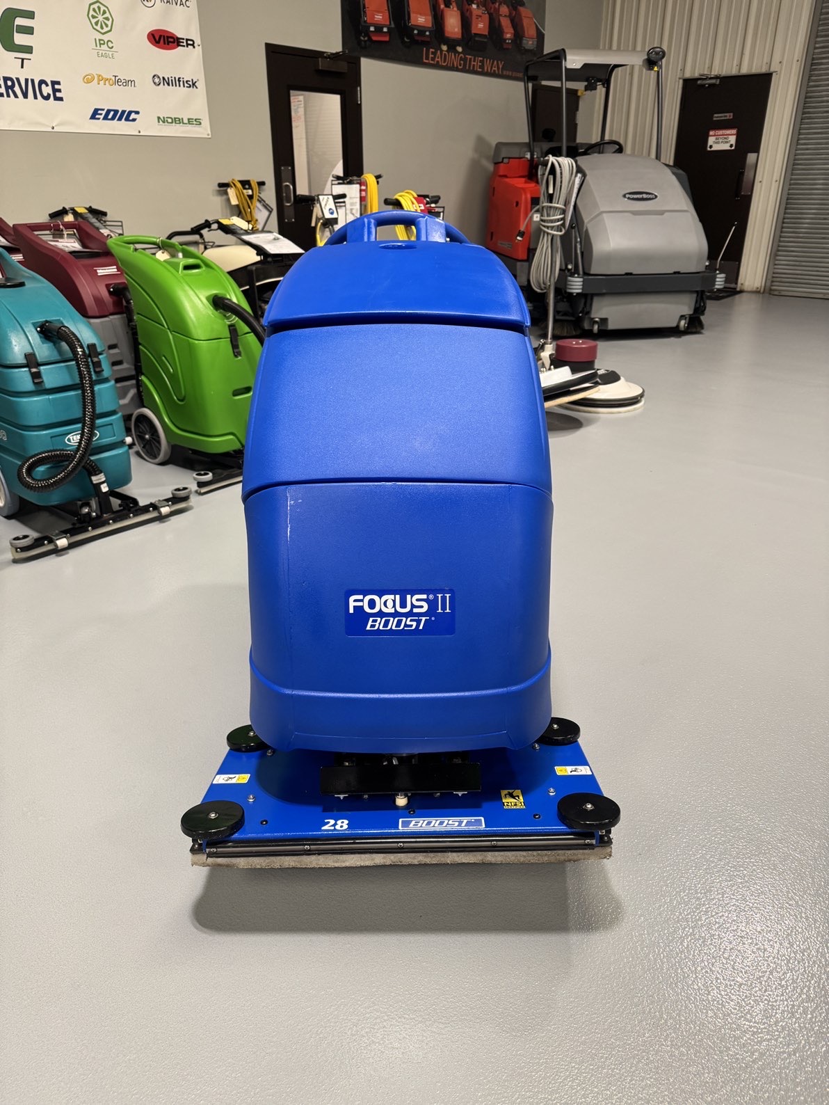 A Clarke Focus II Boost 28" Orbital Scrubber in a warehouse showroom at ChemSource Direct.