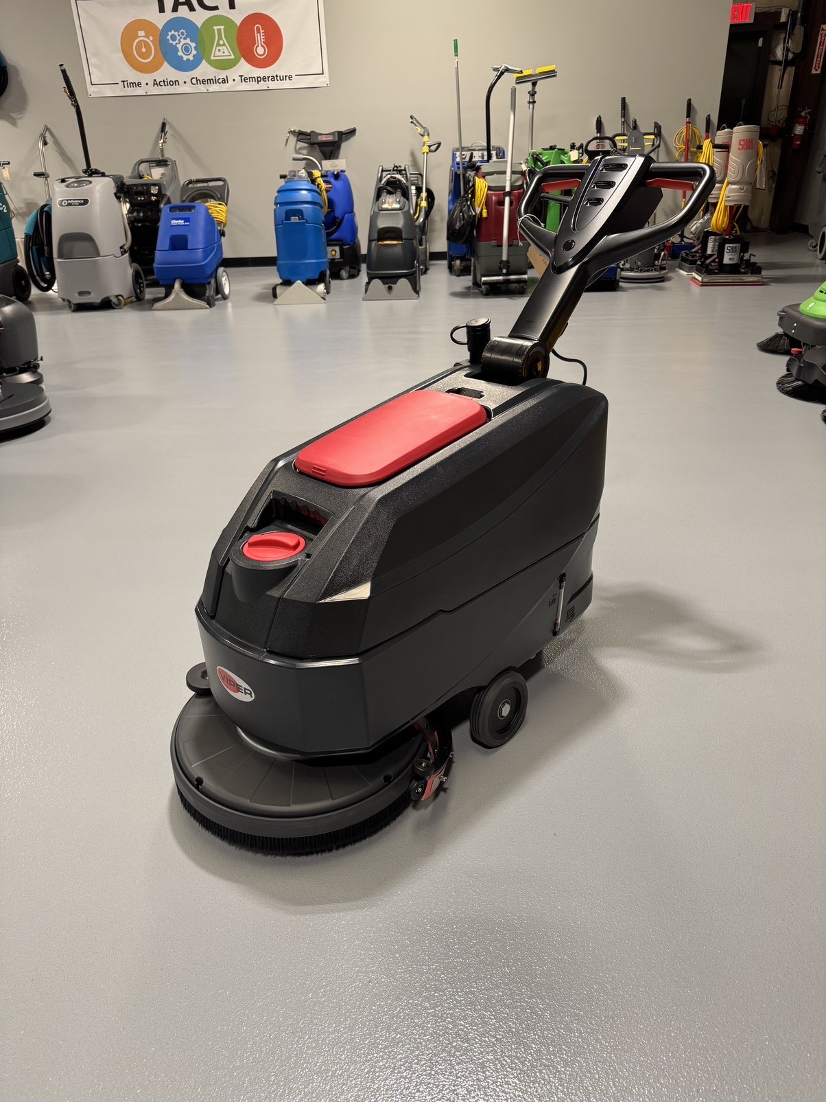 A Viper AS4325B 17" Walk-Behind Scrubber in a warehouse showroom at ChemSource Direct.
