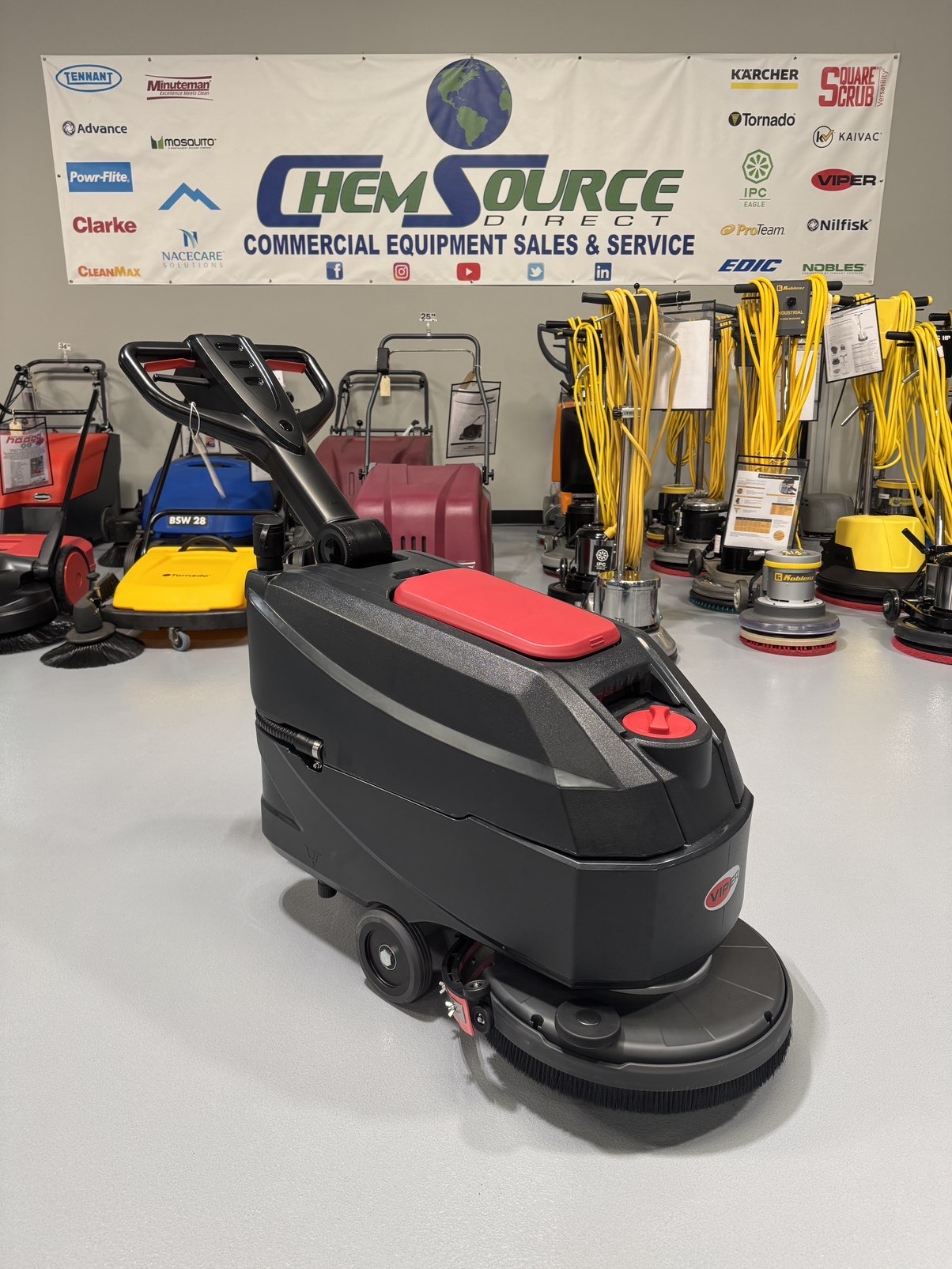 A Viper AS4325B 17" Walk-Behind Scrubber in a warehouse showroom at ChemSource Direct.