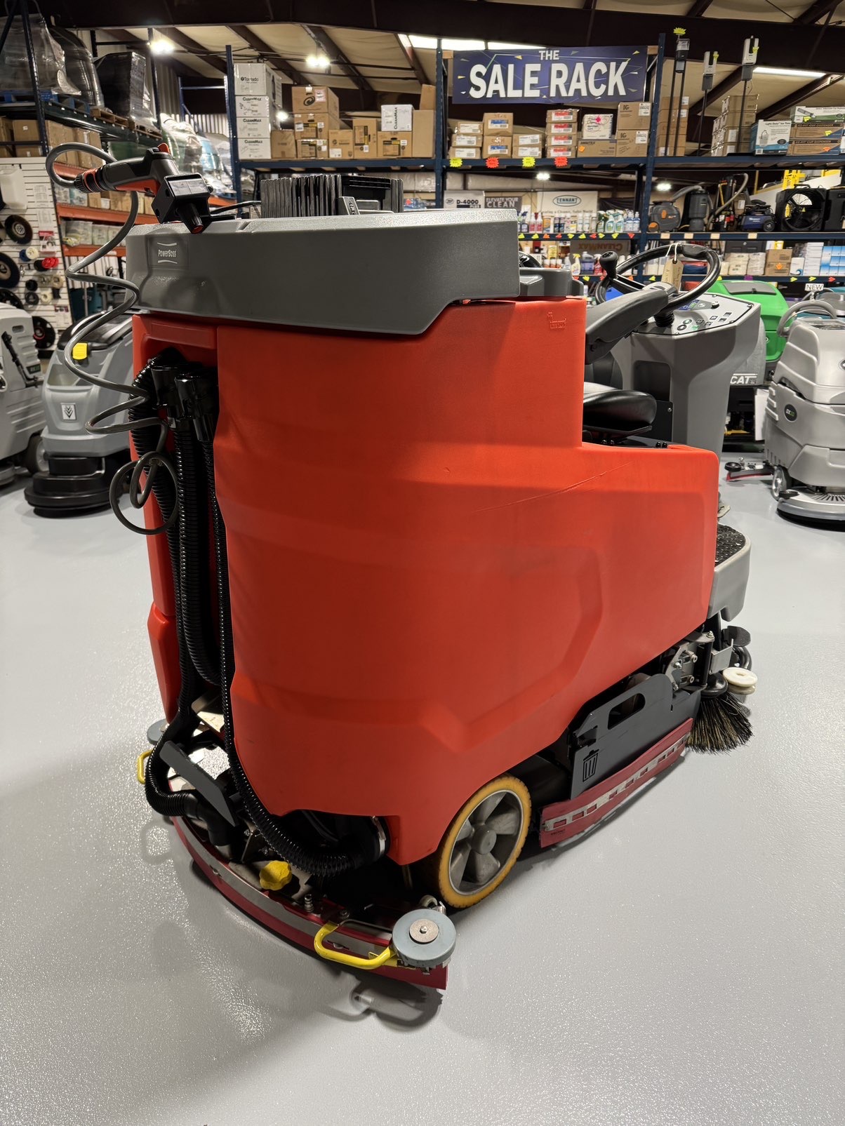 A PowerBoss Scrubmaster B175 Cylindrical Ride-On Scrubber in a warehouse showroom at ChemSource Direct.