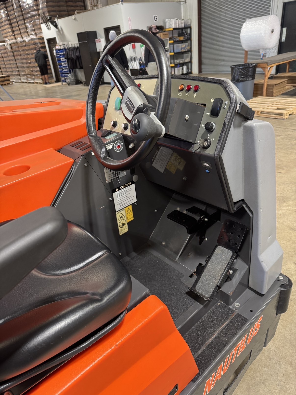 A Powerboss Nautilus PB45LP Ride-On Scrubber in a warehouse showroom at ChemSource Direct.