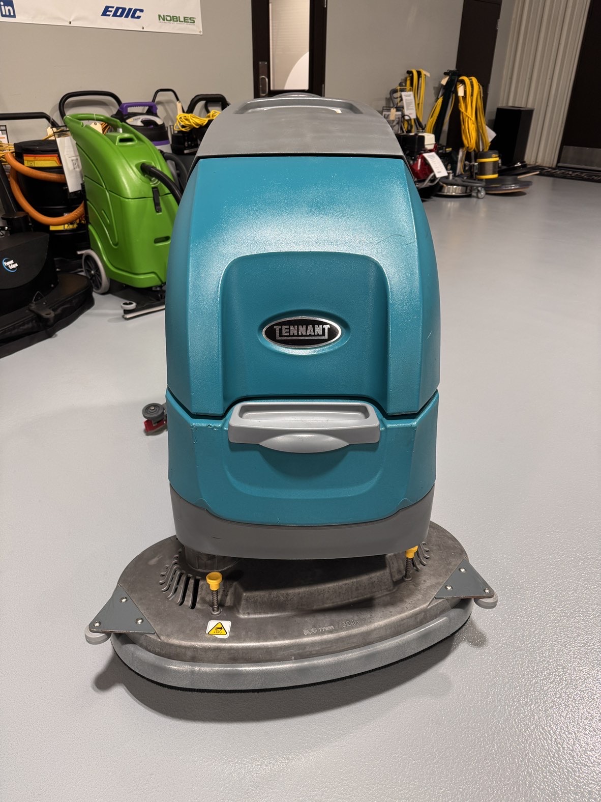 A Tennant T500 Walk-Behind Scrubber in a warehouse showroom at ChemSource Direct.