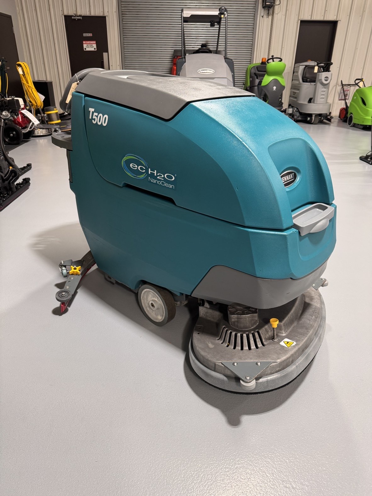 A Tennant T500 Walk-Behind Scrubber in a warehouse showroom at ChemSource Direct.