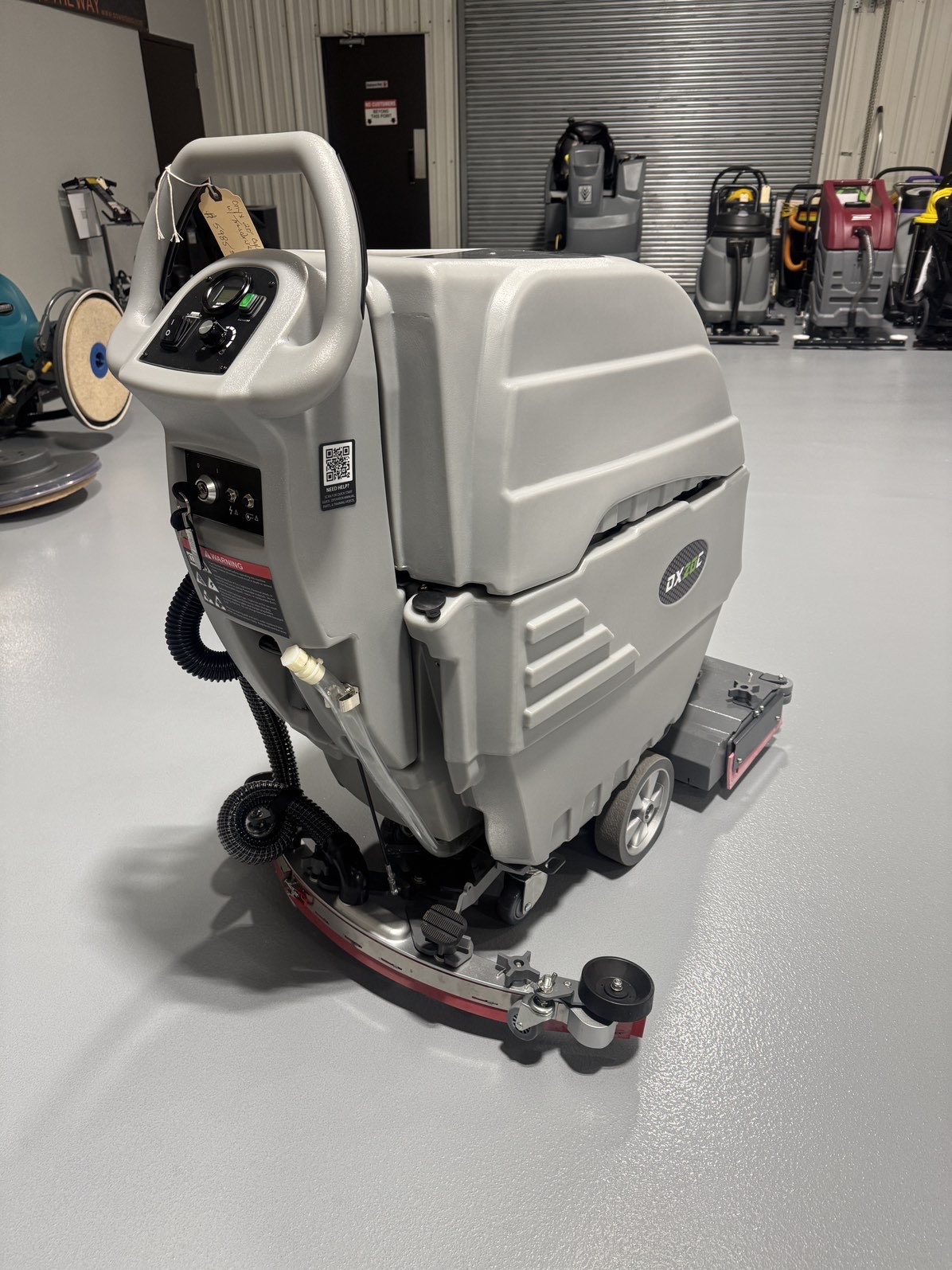 An Onyx DX20C Cylindrical Walk-Behind Scrubber in a warehouse showroom at ChemSource Direct.