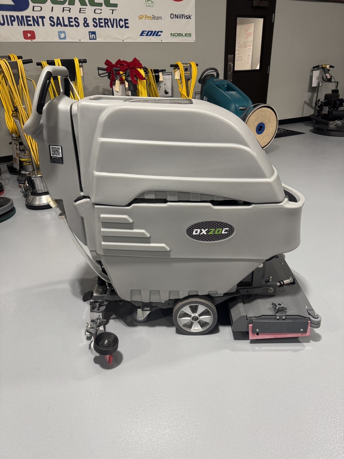 An Onyx DX20C Cylindrical Walk-Behind Scrubber in a warehouse showroom at ChemSource Direct.