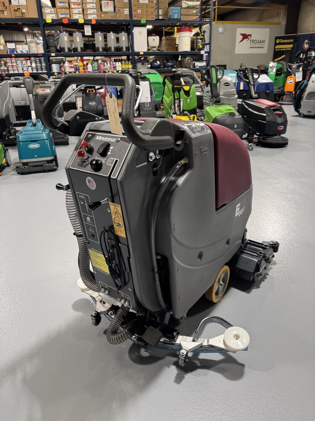 A Minuteman E20CQP Walk-Behind Scrubber in a warehouse showroom at ChemSource Direct.
