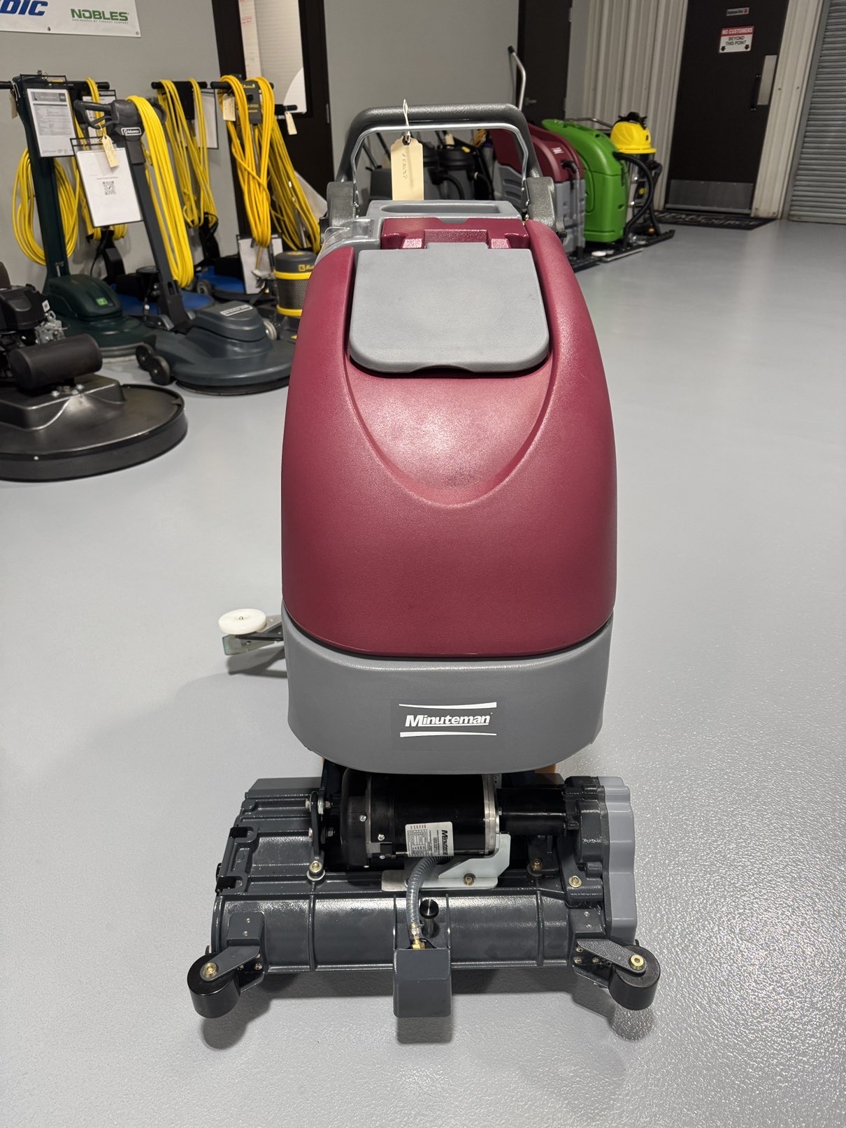 A Minuteman E20CQP Walk-Behind Scrubber in a warehouse showroom at ChemSource Direct.