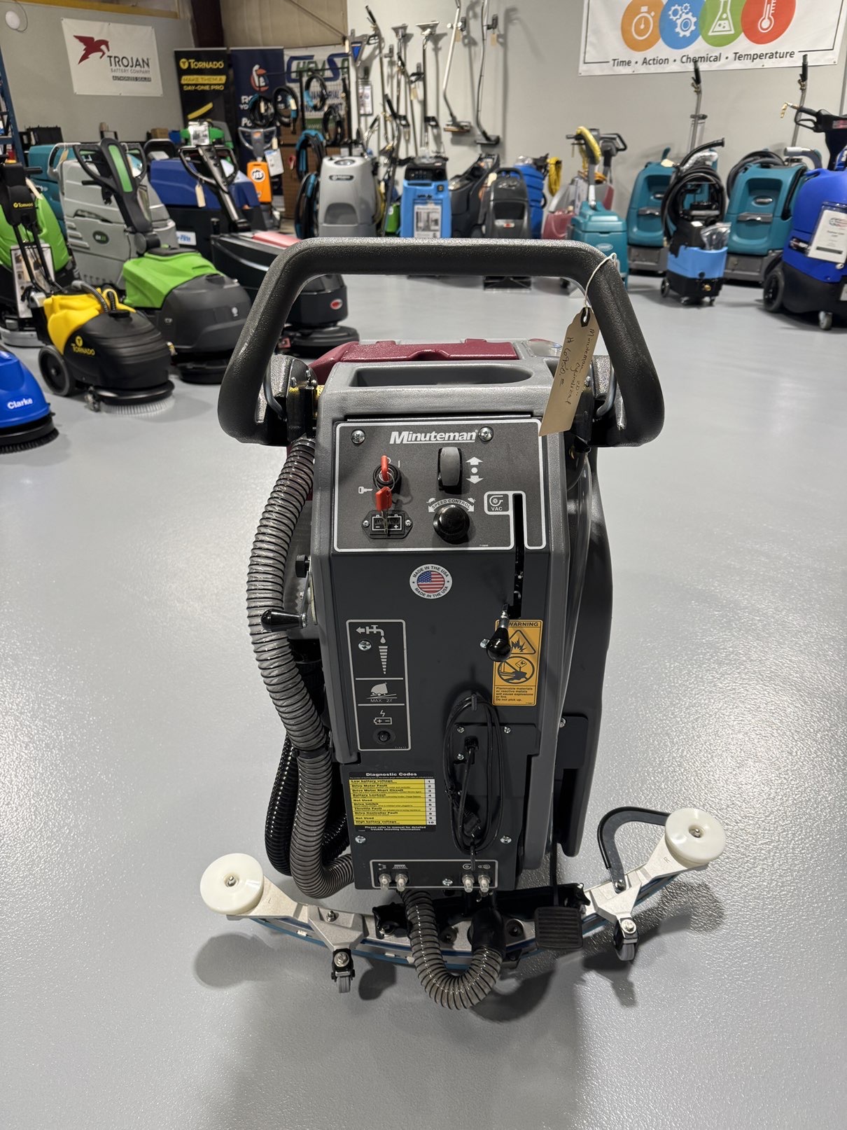 A Minuteman E20CQP Walk-Behind Scrubber in a warehouse showroom at ChemSource Direct.
