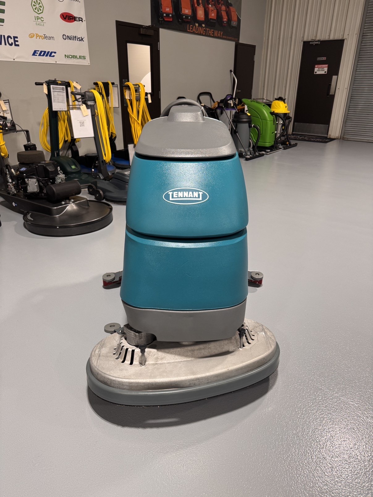 A Tennant T5 32D Disc Walk-Behind Scrubber in a warehouse showroom at ChemSource Direct.