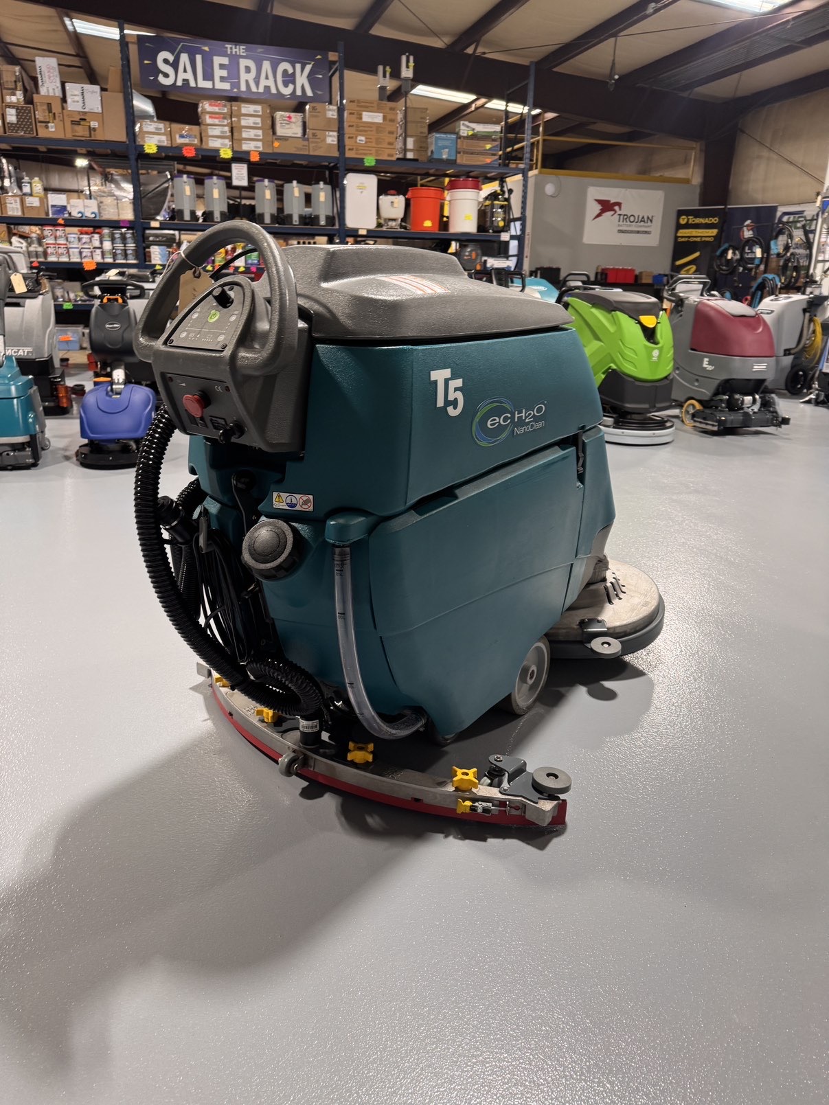 A Tennant T5 32D Disc Walk-Behind Scrubber in a warehouse showroom at ChemSource Direct.