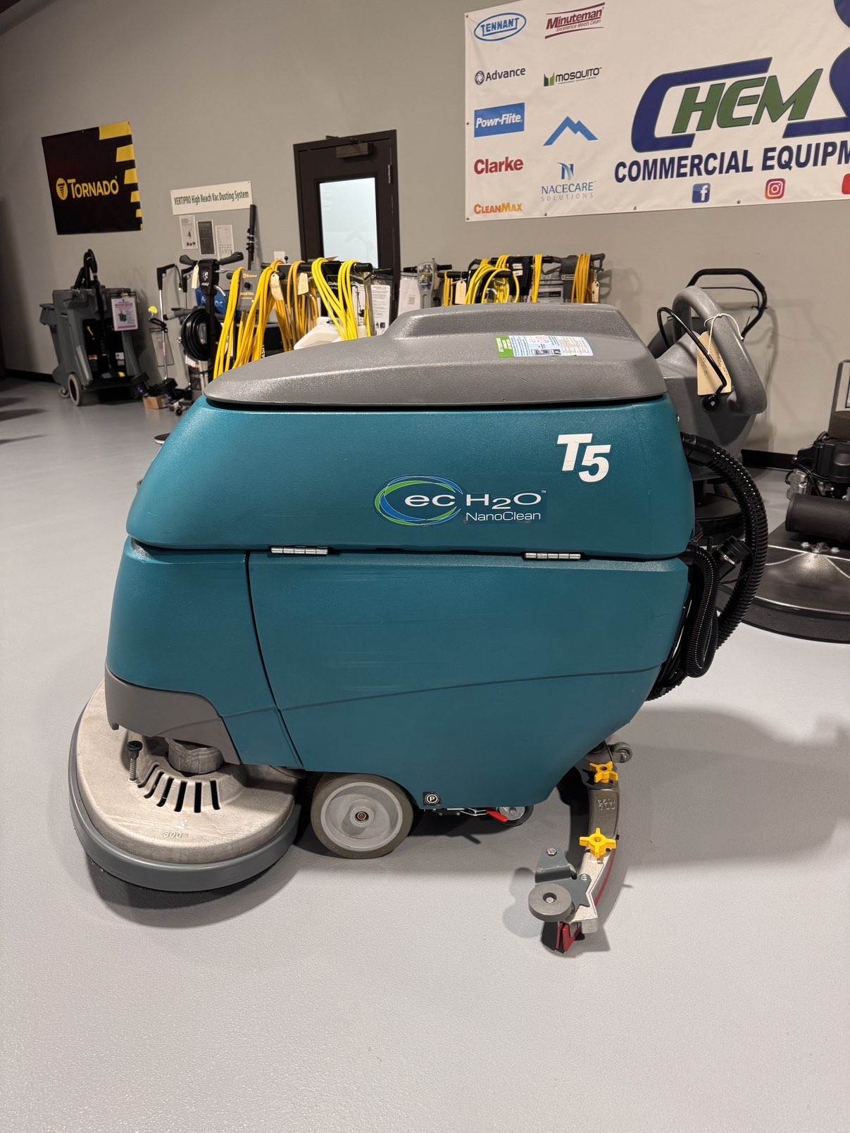 A Tennant T5 32D Disc Walk-Behind Scrubber in a warehouse showroom at ChemSource Direct.