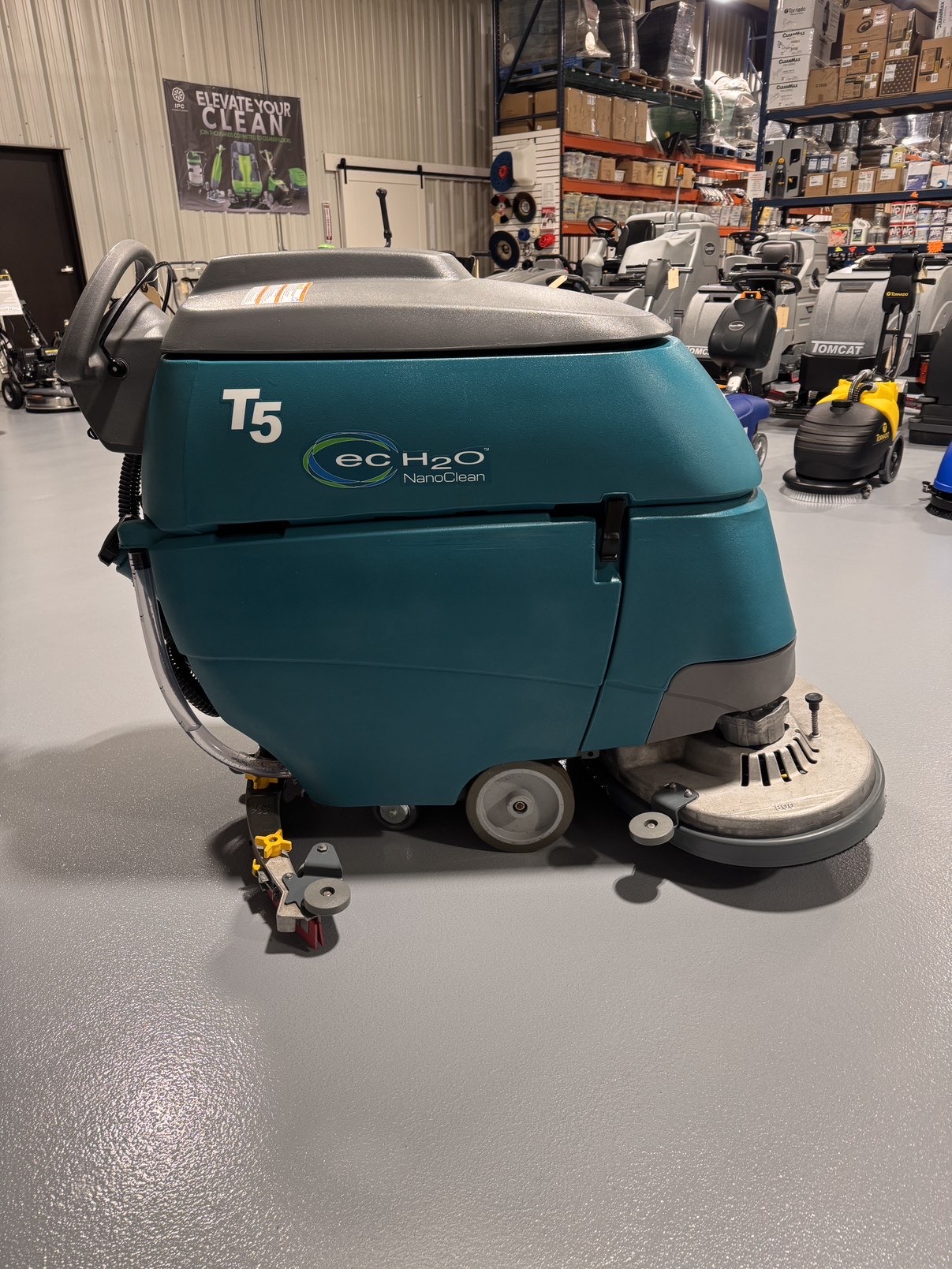 A Tennant T5 32D Disc Walk-Behind Scrubber in a warehouse showroom at ChemSource Direct.
