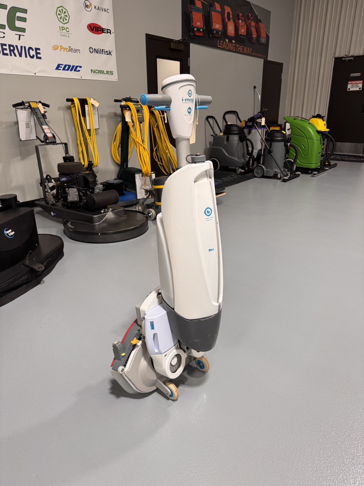 A Tennant iMop XL Plus Walk-Behind Scrubber in a warehouse showroom at ChemSource Direct.