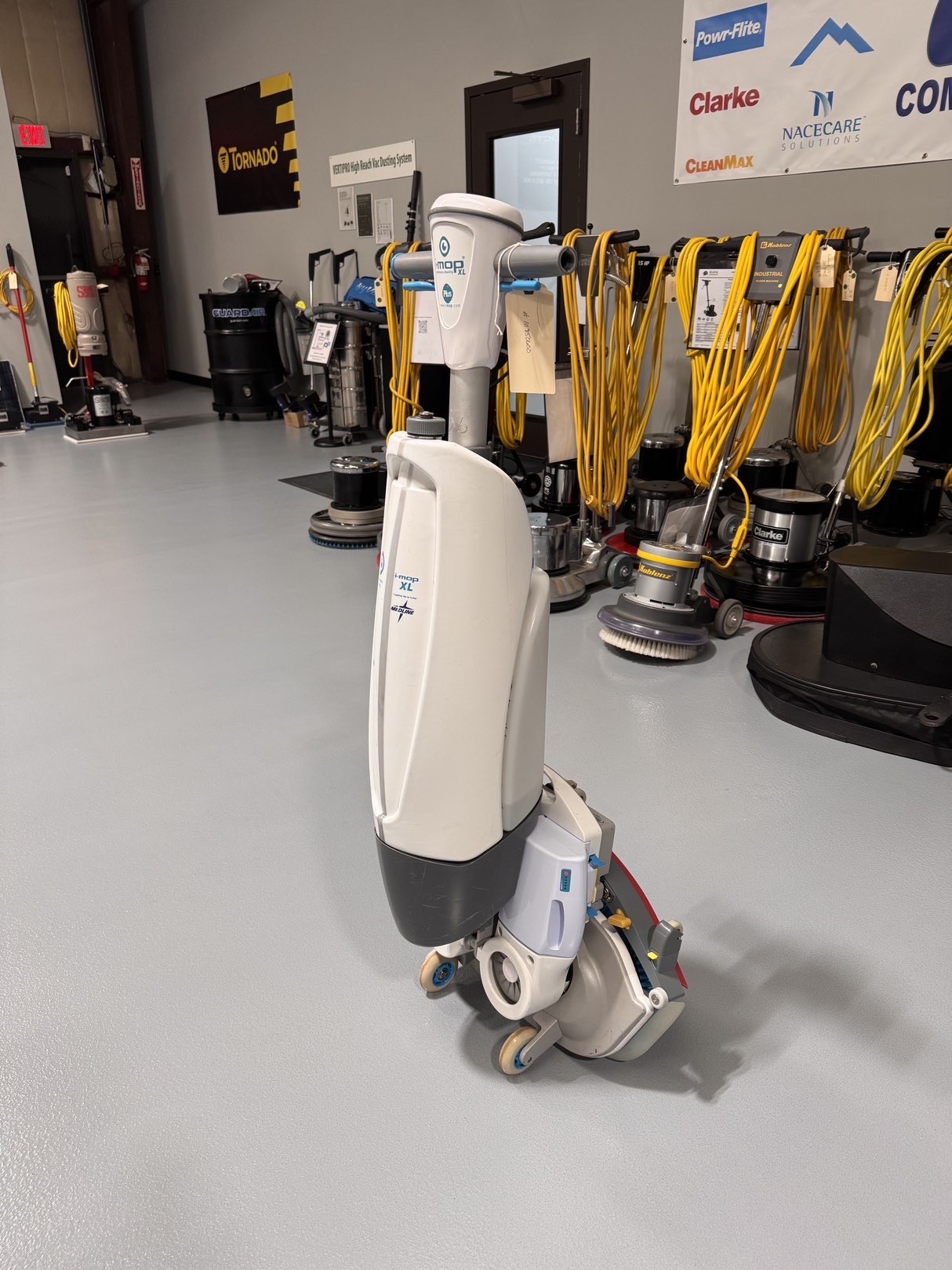 A Tennant iMop XL Plus Walk-Behind Scrubber in a warehouse showroom at ChemSource Direct.