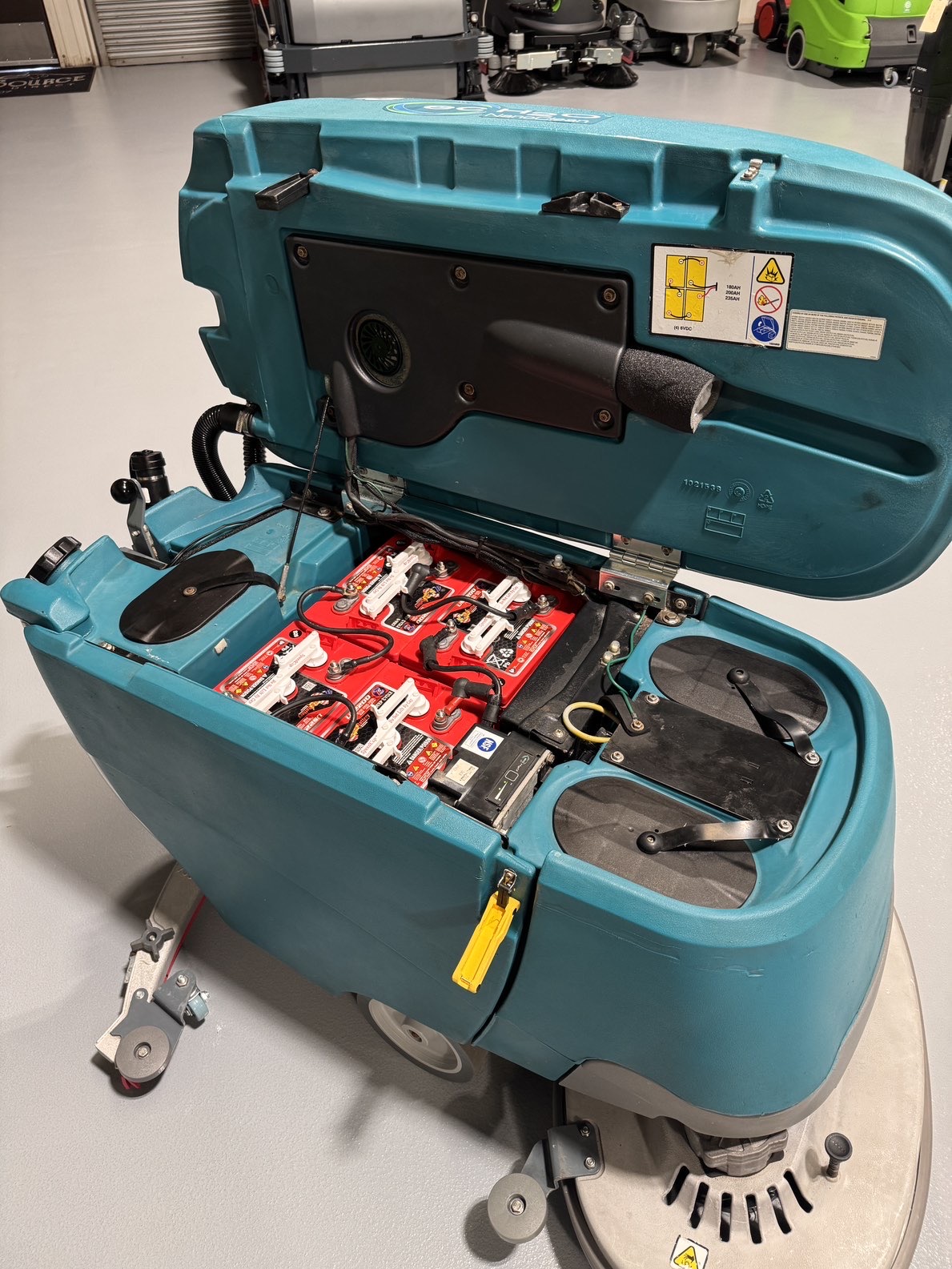 A Tennant T5 32" Walk-Behind Scrubber in a warehouse showroom at ChemSource Direct.