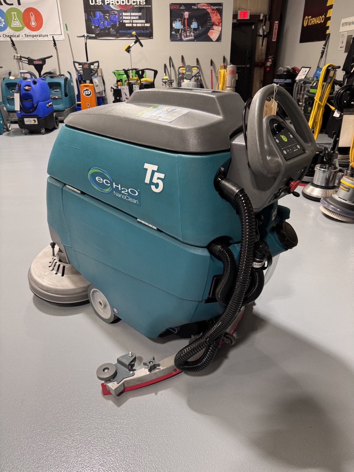 A Tennant T5 32" Walk-Behind Scrubber in a warehouse showroom at ChemSource Direct.
