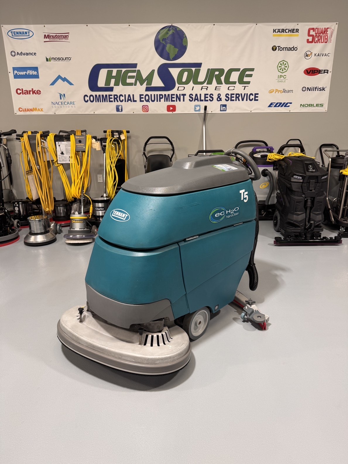 A Tennant T5 32" Walk-Behind Scrubber in a warehouse showroom at ChemSource Direct.