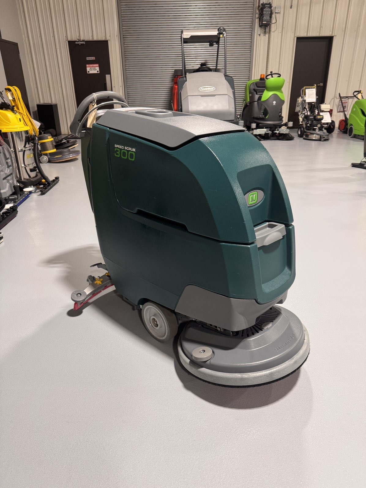 A Nobles SpeedScrub 300 Walk-Behind Scrubber in a warehouse showroom at ChemSource Direct.