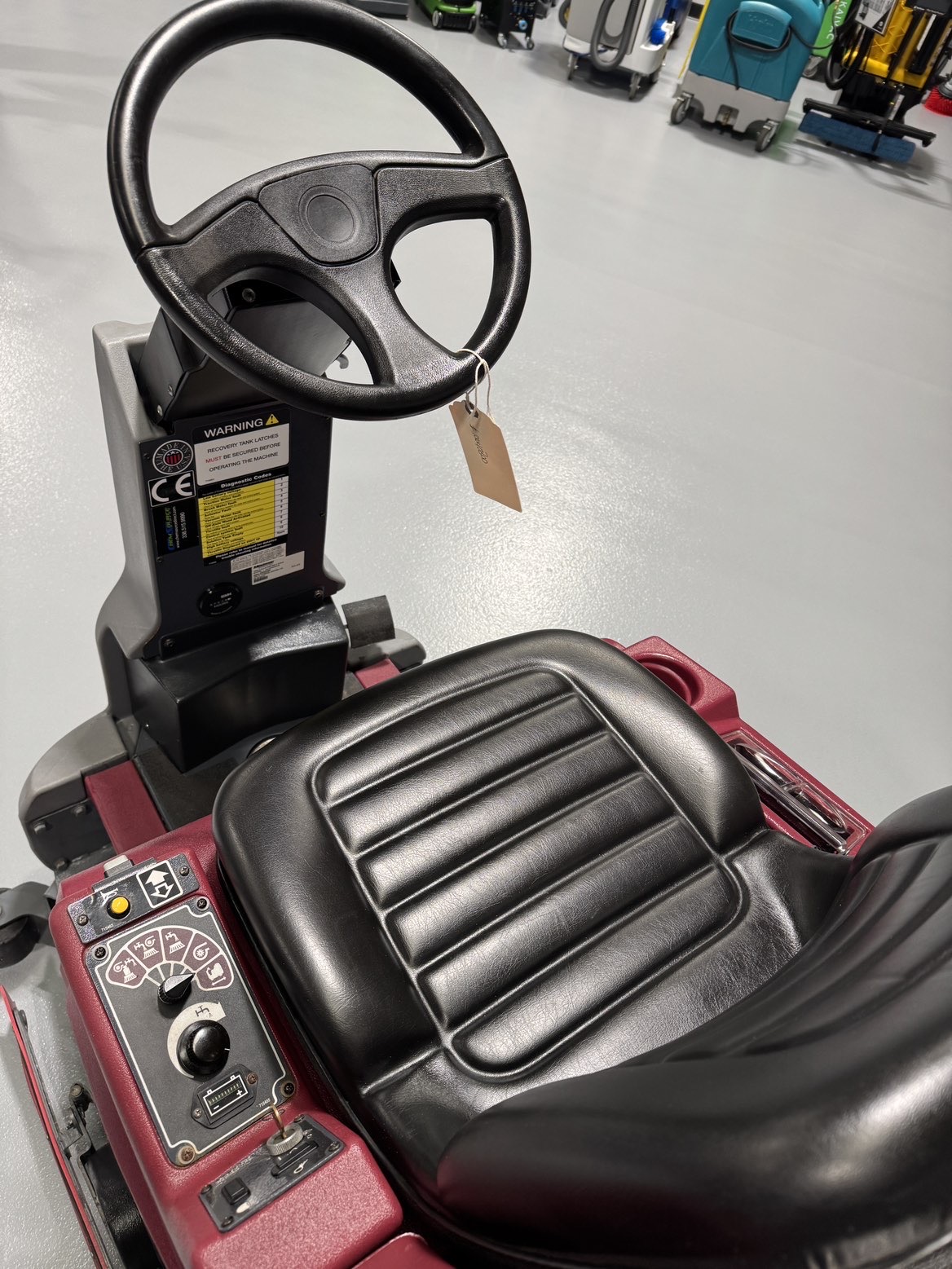 A Minuteman ERide 28/32 Cylindrical Ride-On Scrubber in a warehouse showroom at ChemSource Direct.