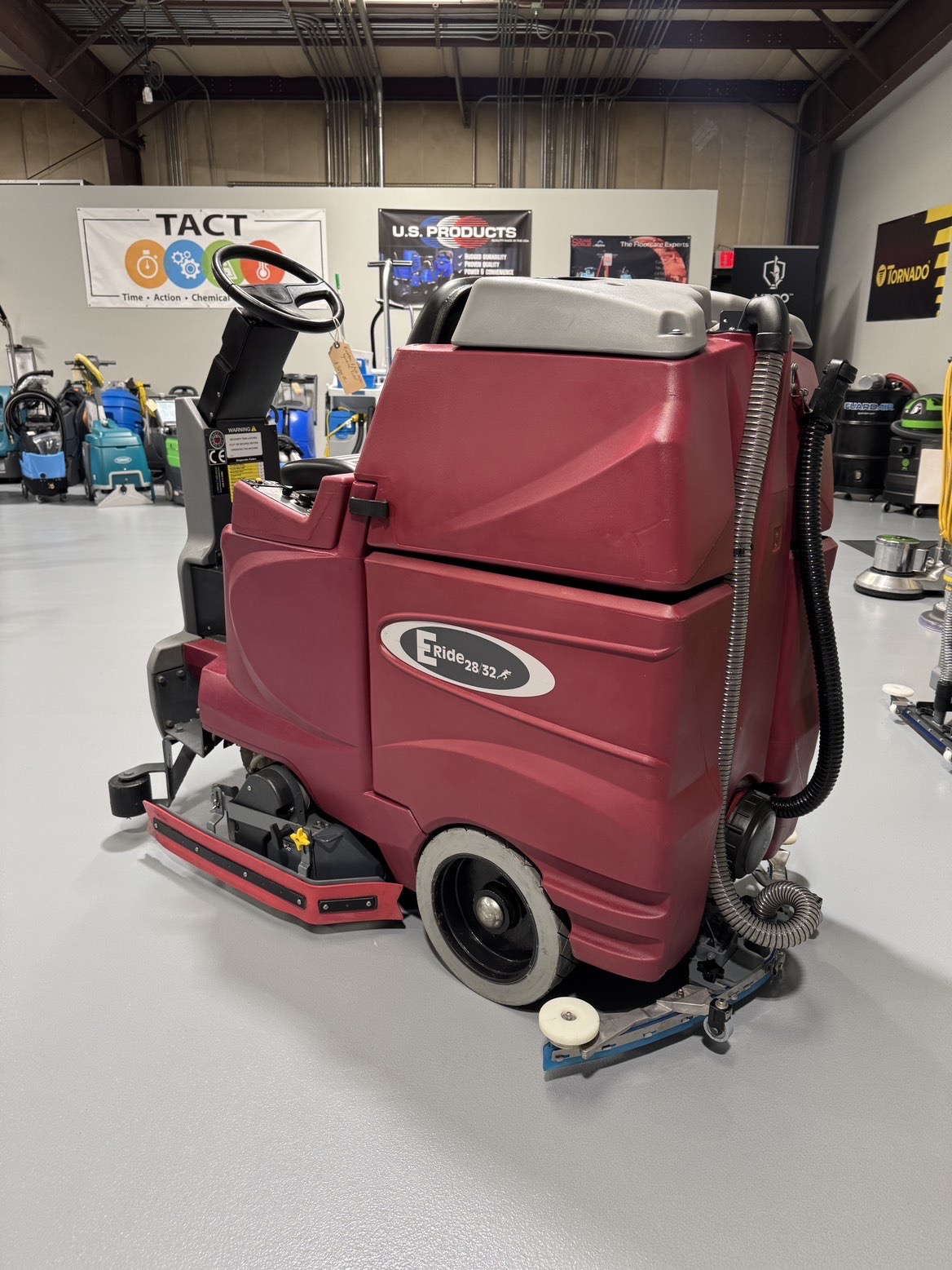 A Minuteman ERide 28/32 Cylindrical Ride-On Scrubber in a warehouse showroom at ChemSource Direct.