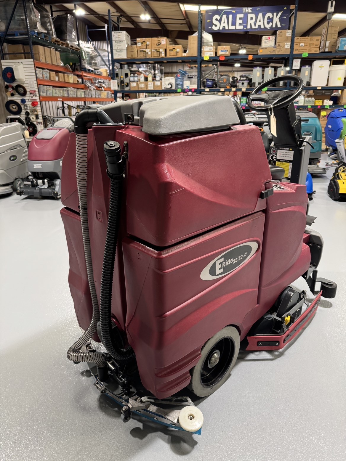 A Minuteman ERide 28/32 Cylindrical Ride-On Scrubber in a warehouse showroom at ChemSource Direct.